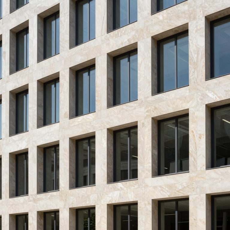 An outdoor architectural shot of a contemporary office building facade clad in premium natural stone under bright daylight.