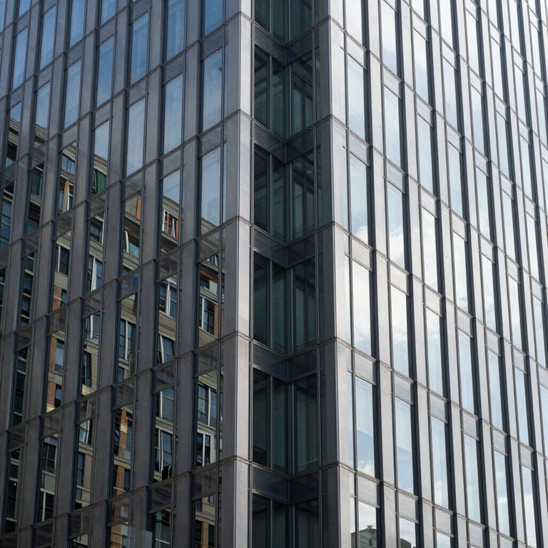Detail of a clean glass and steel office facade reflecting bright daylight, symmetrical framing