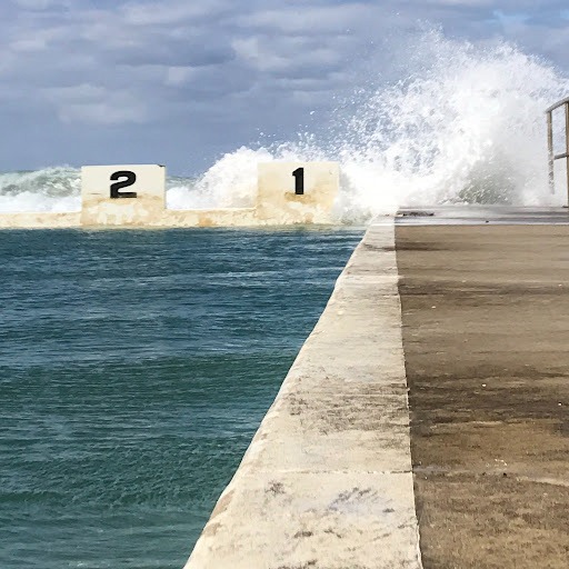 Ocean swimming pool with wave splashing over swim lane starting blocks numbered 1 and 2