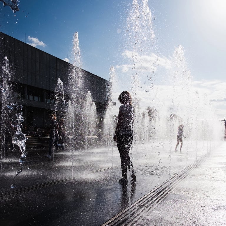 Silhouetted Girl standing in fountain in summer