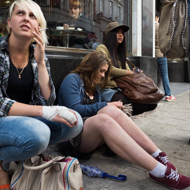 Girls sitting on floor outside shop smoking