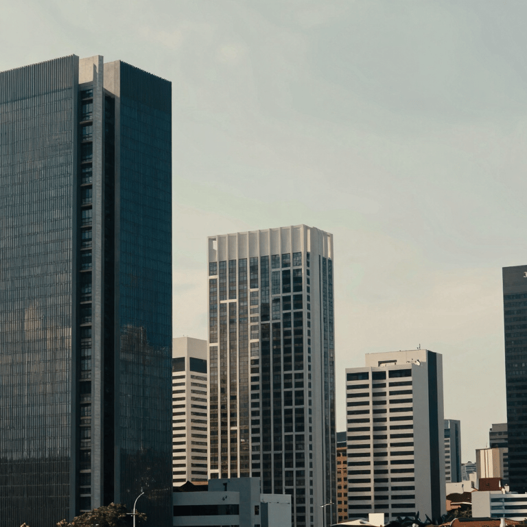 A pair of glasses resting on a tablet with financial spreadsheets in a South American / Brazilian office, muted sage lighting.