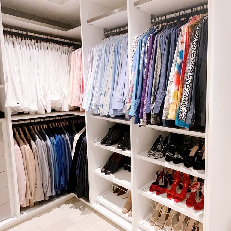 Master closet with hanging clothes on hangers arranged by color and organized perfectly.