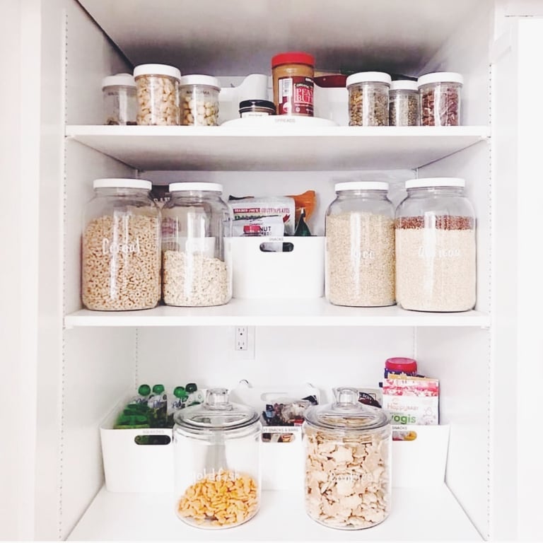 Pantry shelves displayed with food in canisters arranged and organized neatly.