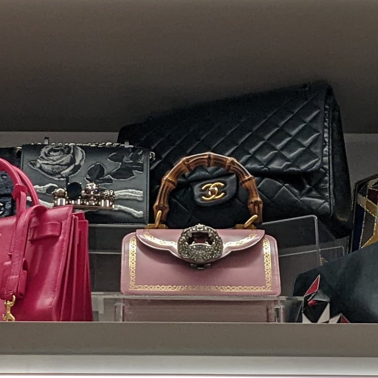 Evening purses on a shelf in a master closet neatly organized with purse stands.