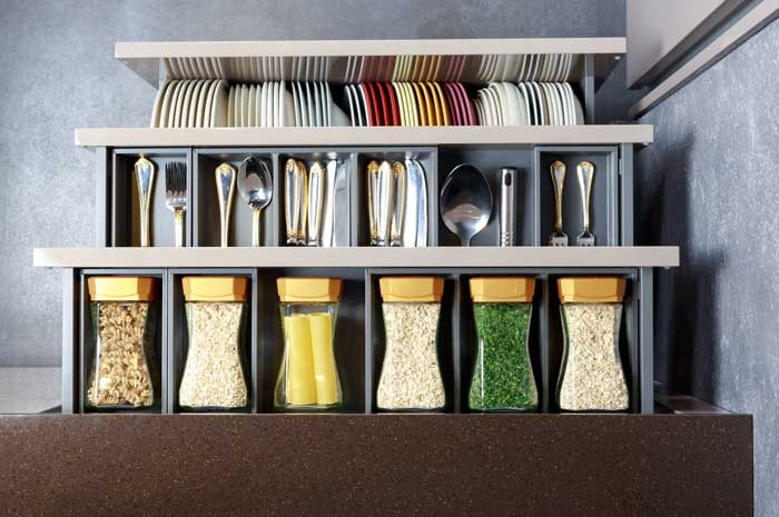 3 drawers in a organized kitchen that contains flatware, spices and plates, neatly arranged  by color