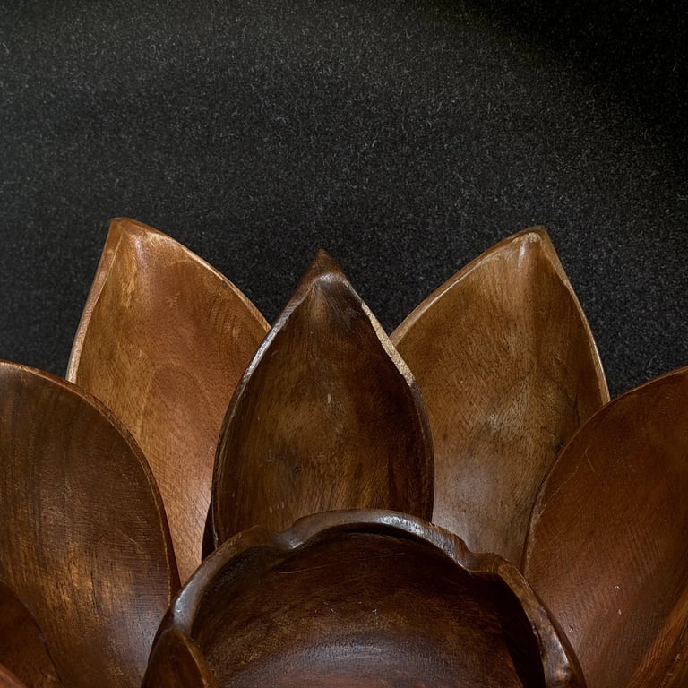 Vintage hanging bamboo wall planter with metal chains casting long shadows on a dimly lit wall.