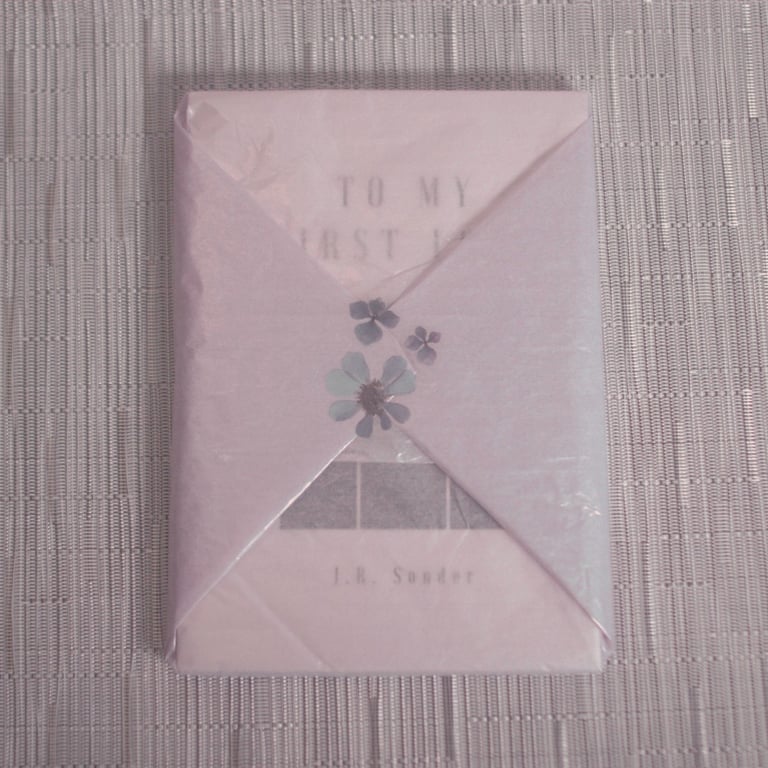 J.R. Sonder's book To My First Love (TMFL) wrapped in purple tissue wrap with a purple flower.