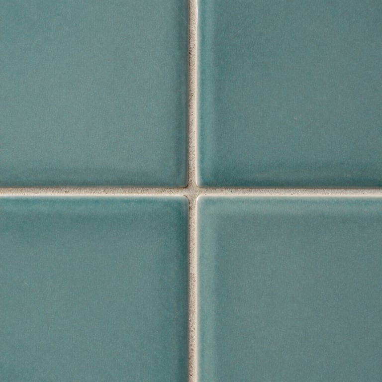 Detailed macro shot of grout lines between muted teal ceramic wall tiles.
