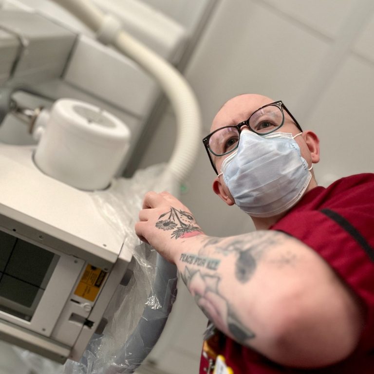 Ben, pictured here in radiographer uniform, operating medical X-ray equipment in a hospital setting.