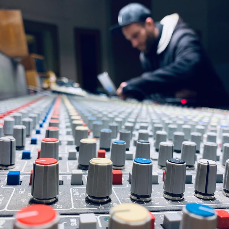 Mixing console close-up with producer working in blurred background