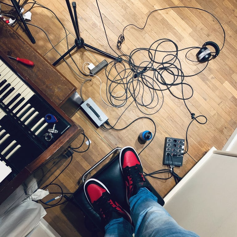 Studio floor with cables, Hammond keys and red sneakers visible