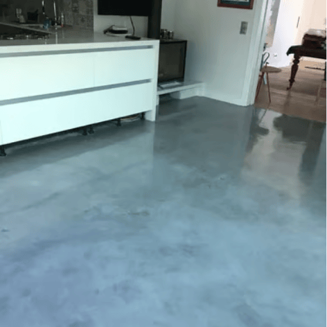 Polished grey microcement floor with a high-gloss finish in a modern open-plan kitchen area.