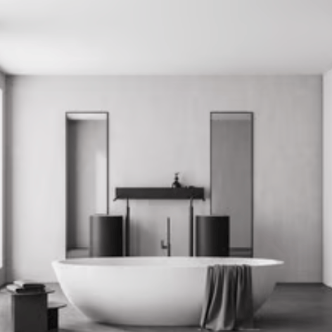 Modern minimalist bathroom featuring a white freestanding soaking tub and dual black pedestal sinks.