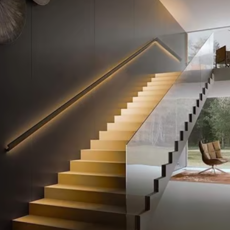 Modern floating wooden staircase with glass railing and integrated LED wall handrail lighting.