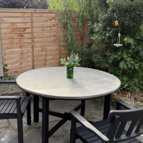 A microcement garden table with black microcement chairs in a courtyard