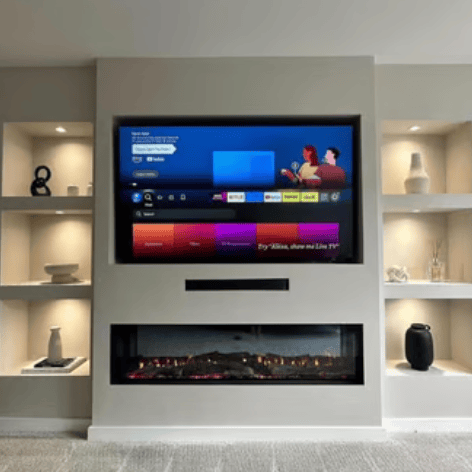 Modern media wall featuring a recessed smart TV, electric fireplace, and illuminated alcove shelving.