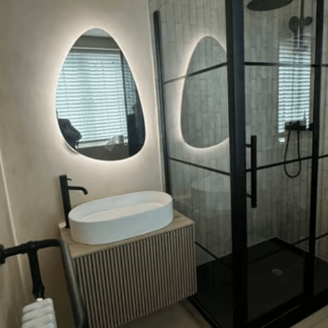 Modern bathroom with microcement finish, backlit mirror with stones.