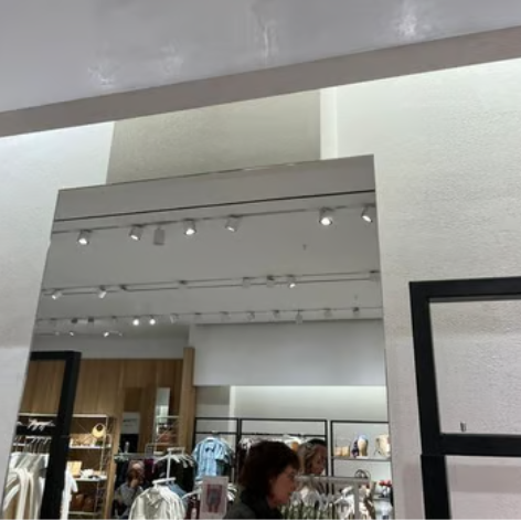 A large rectangular mirror in a modern clothing store with microcement application reflecting the li