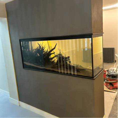 Custom built-in aquarium with live plants and driftwood integrated into a modern gray microcement