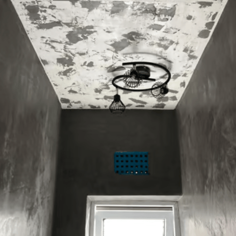 Modern industrial hallway with grey microcement walls and a unique black metal pendant light.