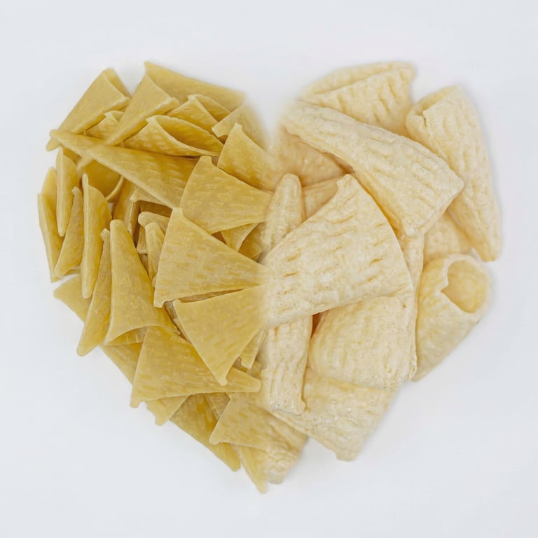 Raw and fried cone-shaped corn chips arranged in a heart shape on a white background.