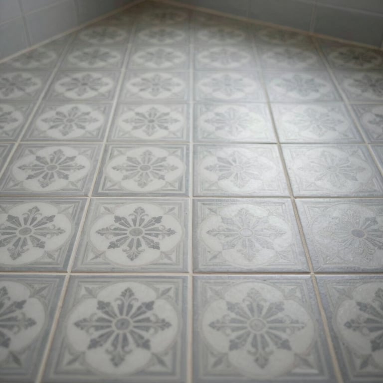 A beautifully tiled bathroom floor with intricate patterns in light grey and white, showcasing expert craftsmanship and a clean aesthetic.