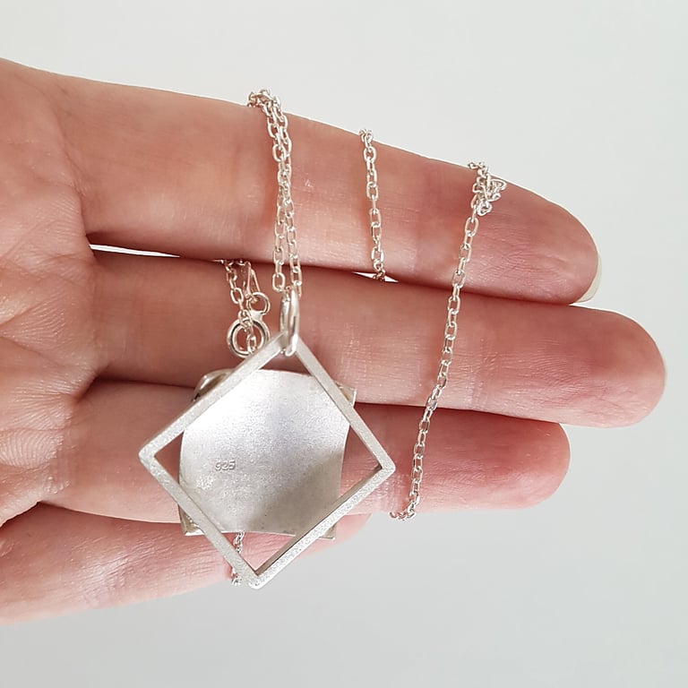 Hand holding a handmade 925 sterling silver geometric square pendant necklace with a minimalist link chain.