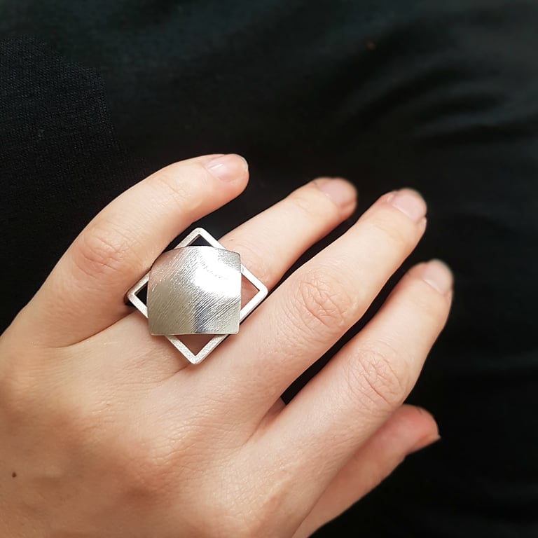 a woman's hand holding a silver ring