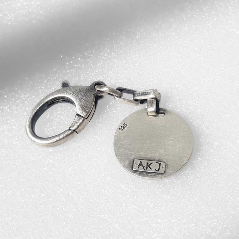 Oxidized sterling silver 925 lobster claw clasp with a round designer charm featuring an AKJ hallmark.