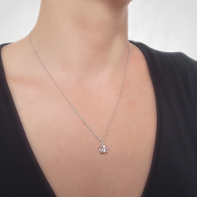a woman wearing a black top and a necklace with a pink heart