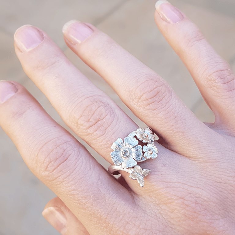 a woman's hand holding a ring with flowers