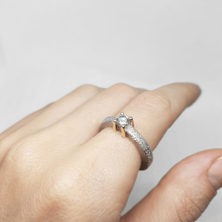 a person's hand holding a ring with a diamond