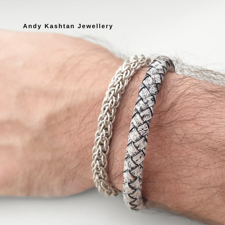Handcrafted sterling silver chain and woven leather designer bracelets worn on a man's wrist.