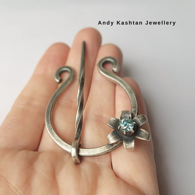 Handmade sterling silver penannular brooch featuring a gemstone flower detail for scarves and shawls.