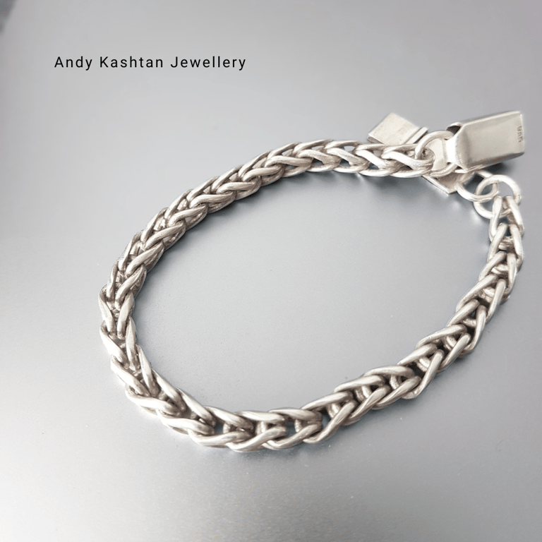 Handmade sterling silver braided chain bracelet by Andy Kashtan Jewellery on a metallic background.