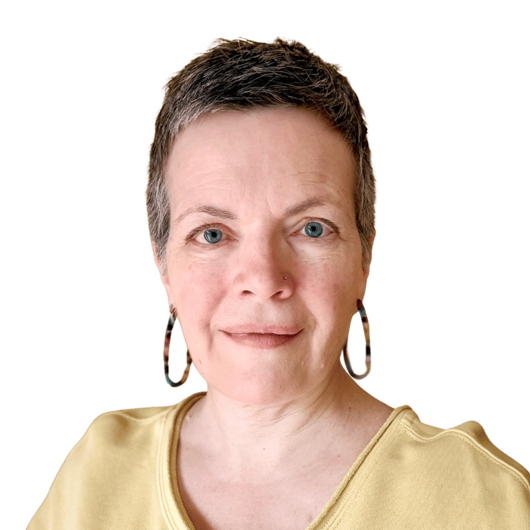 Head & shoulders photo of middle aged woman with short greying hair and blue eyes