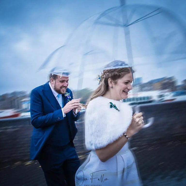 wedding couple with umbrellas running from the rain