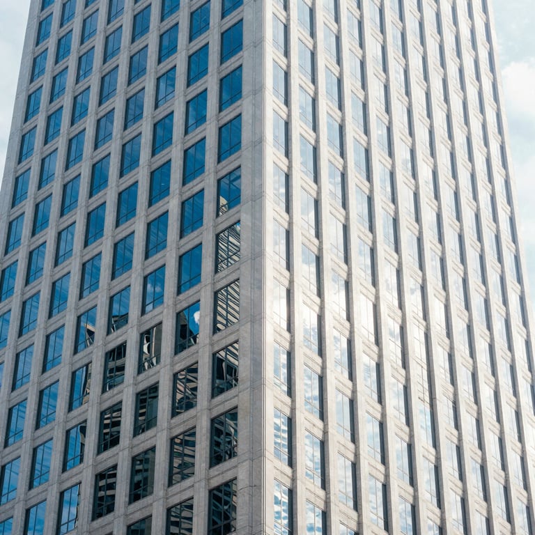 Bright architectural detail of a modern skyscraper in a US business district, reflecting off-white and cool blue tones.