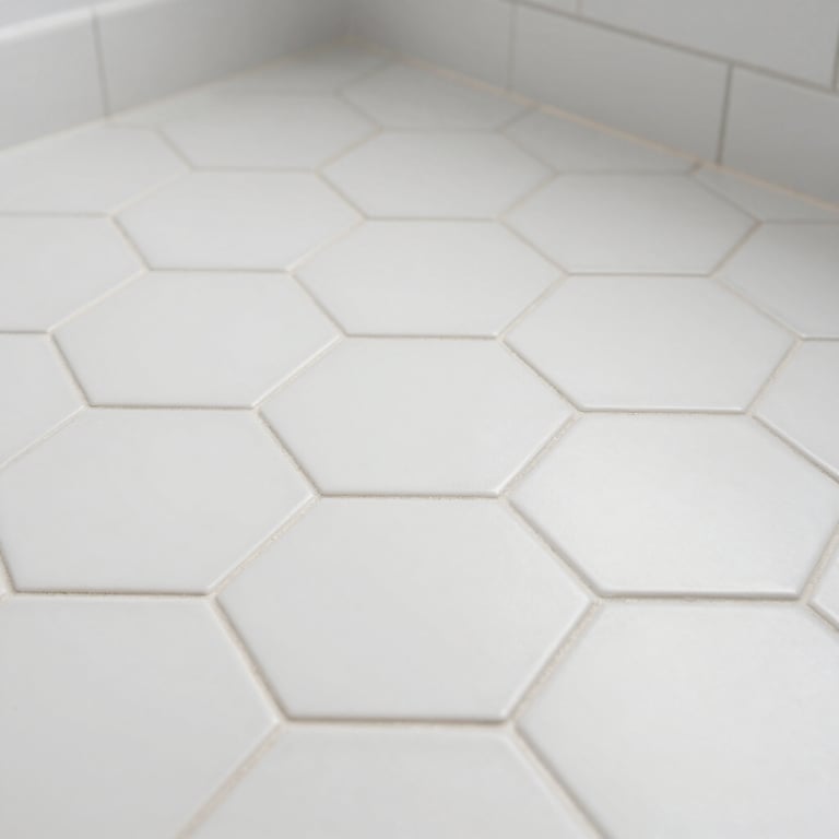 Detail shot of pristine white hexagonal floor tiles with clean grout lines in a newly renovated bathroom.