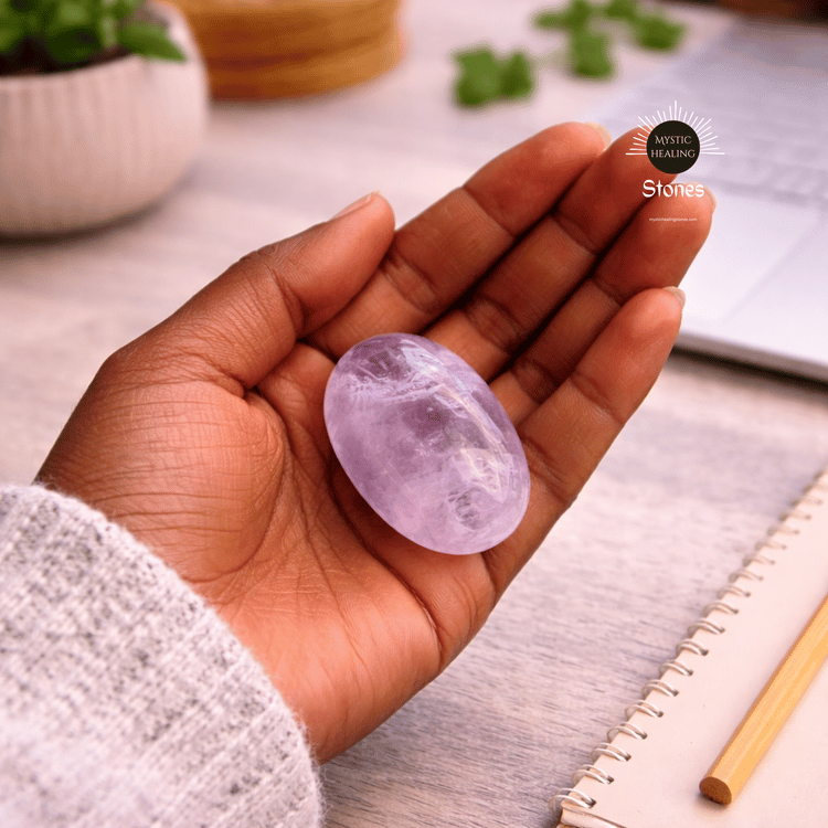 A person holding a smooth, purple amethyst worry stone for crystal healing and stress relief.