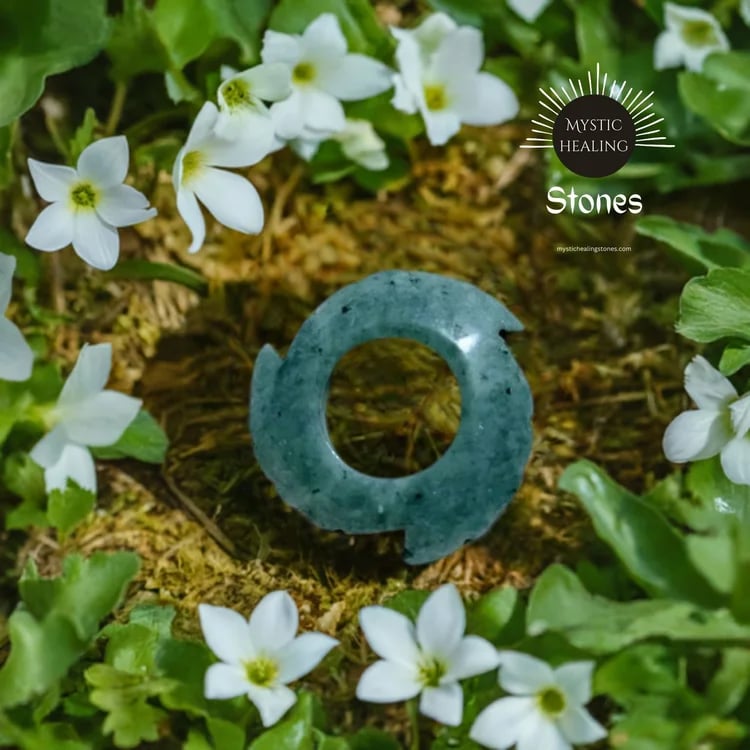Polished green jade crystal stone resting on moss surrounded by delicate white wildflowers.