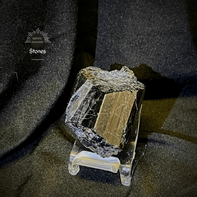 A raw black tourmaline crystal cluster on a clear display stand for protection and grounding.
