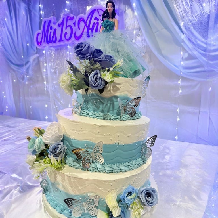Pastel de quinceañera azul claro y blanco de tres niveles decorado con rosas, mariposas y un adorno 
