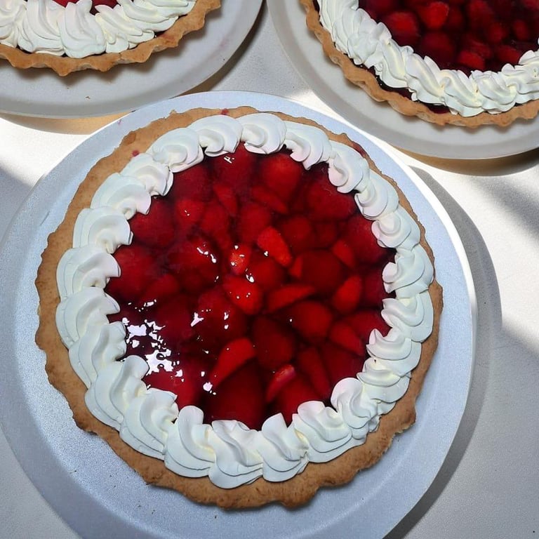 Tarta de fresa fresca con glaseado y glaseado de crema batida en un plato blanco.