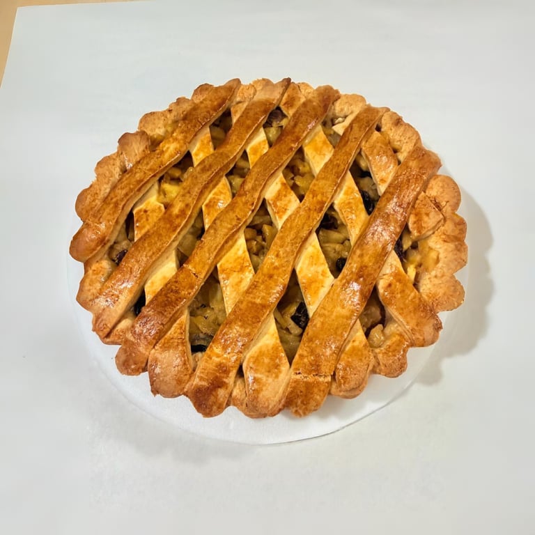 Pastel de manzana casero recién horneado con una corteza de celosía dorada sobre un fondo blanco.