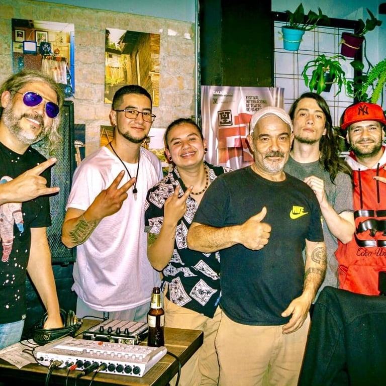 Un grupo de hombres sonrientes posando junto a un controlador y una consola de DJ en un evento 