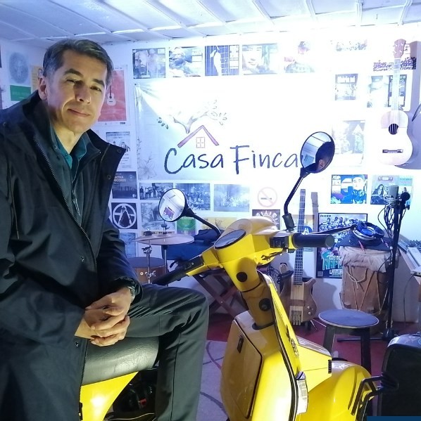 Un hombre está sentado en una motoneta amarilla dentro del estudio musical de Casa Finca