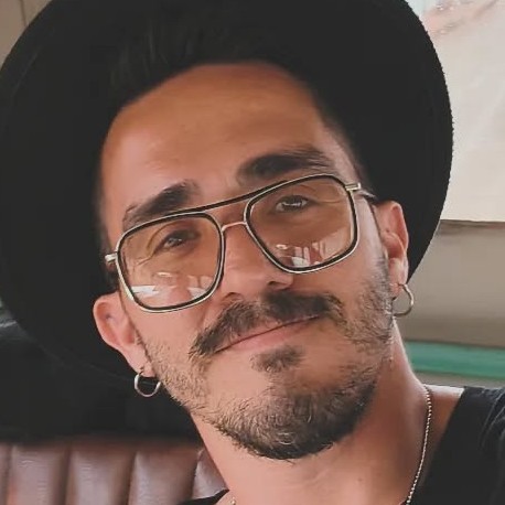 Un hombre con estilo, usando un sombrero negro de ala ancha y gafas aviador con lentes amarillos