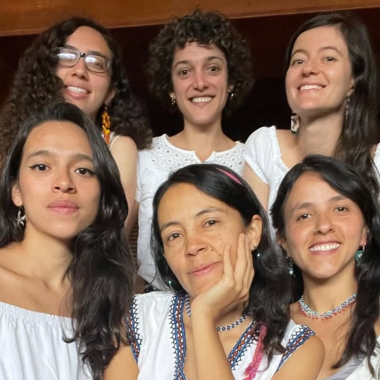Un grupo diverso de seis mujeres sonrientes, vestidas con blusas blancas, posando juntas 